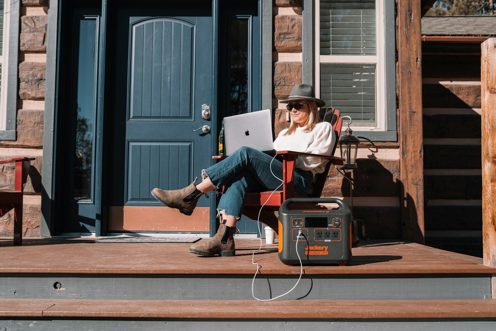 A portable power station charging a laptop on a front porch