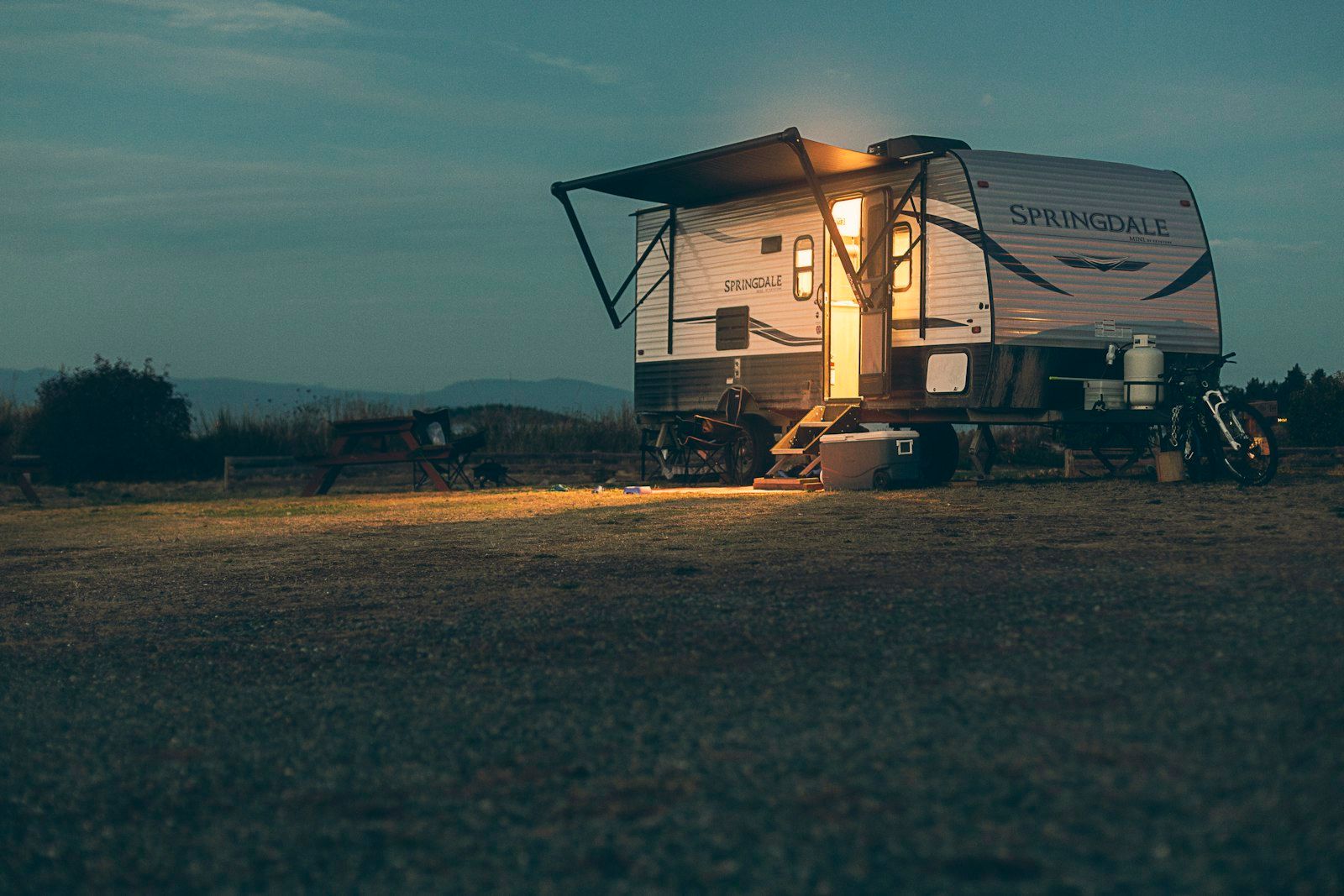 A camper trailer with its lights on at dusk